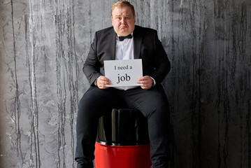 sad caucasian man looking for new job due to drop in oil prices. man sits on oil barrels, his company has failed in world market