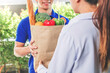 © joyfotoliakid - Food Delivery concept. Asian woman hand accepting bag of food, fruit, vegetable delivery from professional deliveryman Postman and express grocery delivery.