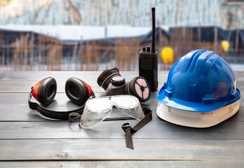 Wall Mural - Work safety protection equipment. Industrial protective gear on wooden table, blur construction site background.
