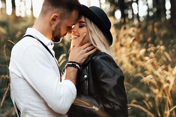 Amazing smiling wedding couple. Pretty bride and stylish groom. Bride and groom are standing face to face with the green forest and mountaints on background.