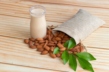 Wall Mural - Almond milk in glass with almonds on wooden table
