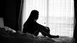 © Kenstocker - silhouette of alone woman sitting on the bed beside the windows with sunlight in the morning