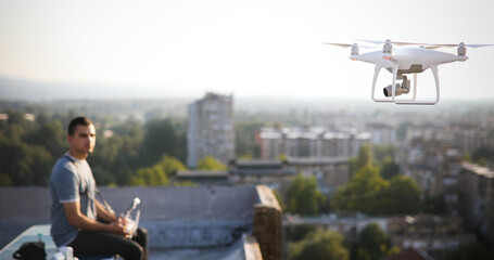 Young technician flying UAV drone with remote control on rooftop