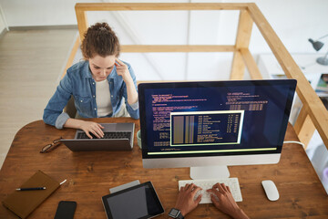 Wall Mural - high angle portrait of young woman using laptop while working at desk in software development agency