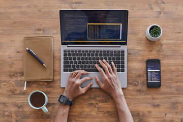 Wall Mural - top down view at male hands typing on laptop keyboard while writing code at textured wooden desk in 