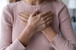 Crop close up of woman hold hands on breast heart show support to sick people, young female feel thankful grateful, demonstrate appreciation and gratitude, volunteer help, healthcare concept