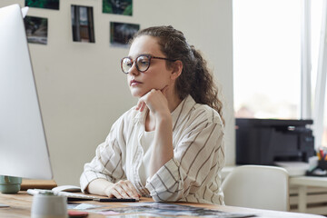 Wall Mural - portrait of modern young woman wearing glasses looking at computer screen pensively while working at