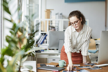 Wall Mural - portrait of creative young woman reviewing photographs while working on editing and publishing in mo