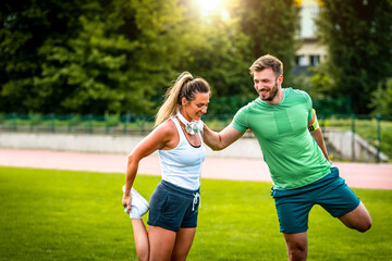 Wall Mural - Smiling couple stretching after training in park