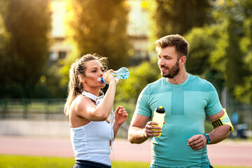 Wall Mural - Handsome healthy couple on water break during training in park