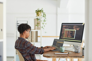 Wall Mural - side view at african-american it developer typing on keyboard with black and orange programming code