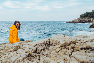 Poster - woman siting on the edge of the cliff looking on big waves