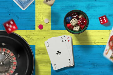 Wall Mural - Sweden casino theme. Aces in poker game, cards and chips on red table with national flag background. Gambling and betting.