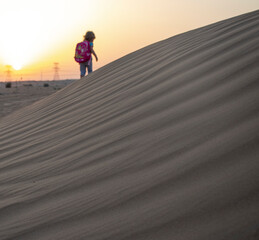 Kid walks towards the sunset in the desert