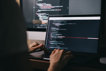 Young caucasian female programmer in glasses writes program code on a laptop computer. home office