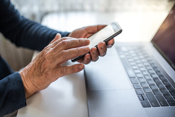 Senior person using mobile phone and laptop at home