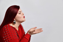 Fat Ginger Female In Red Spiked Blouse And Earrings. Closed Her Eyes, Sending An Air Kiss, Posing Isolated On White Background