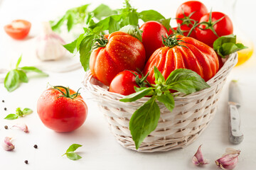 Assorted fresh ripe tomatoes and basil in basket.  Healthy food concept. Clean eating