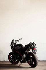 Wall Mural - Sports black motorcycle on a background of an underground gray wall in the studio.