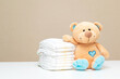 Stack of diapers with toy teddy bear on table. set for boy girl for baby shower with copy space