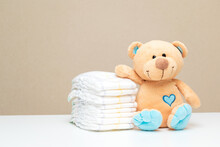 Stack Of Diapers With Toy Teddy Bear On Table. Set For Boy Girl For Baby Shower With Copy Space