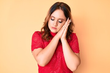 Young beautiful caucasian woman wearing casual clothes sleeping tired dreaming and posing with hands together while smiling with closed eyes.