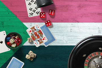 Wall Mural - Sudan casino theme. Aces in poker game, cards and chips on red table with national wooden flag background. Gambling and betting.