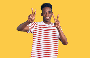 Young african american man wearing casual clothes smiling looking to the camera showing fingers doing victory sign. number two.