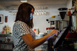 © Guillem de Balanzó - an caucasian cafe owner businesswoman taking order from her customer at counter using digital tablet.