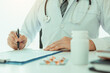 © wutzkoh - Doctor hand holding pen writing patient history list on note pad and talking to the patient about medication and treatment.