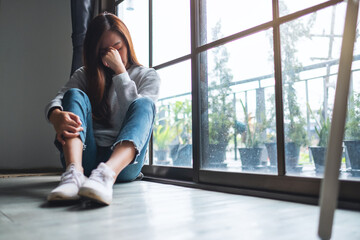 Wall Mural - A sad and stressed young asian woman sitting alone in the room