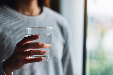 Wall Mural - Closeup image of a woman holding a glass of pure water