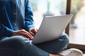 Closeup image of a woman using , working and typing on laptop computer