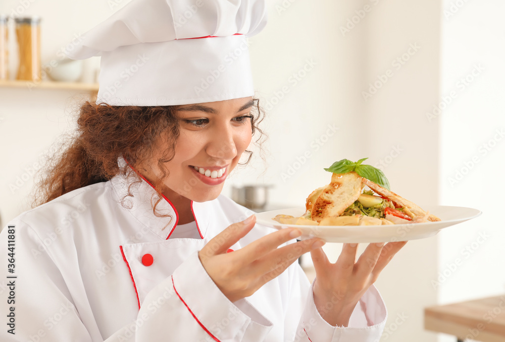 Female African-American chef with tasty dish in kitchen