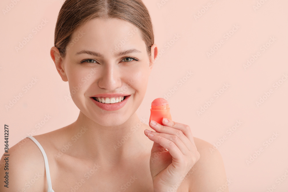 Beautiful young woman with lip balm on color background