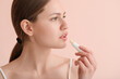 © Pixel-Shot - Beautiful young woman with lip balm on color background
