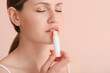 © Pixel-Shot - Beautiful young woman with lip balm on color background