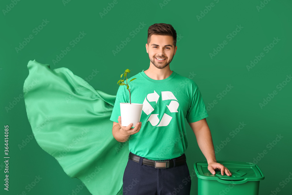 Man dressed as eco superhero with trash bin and plant on color background