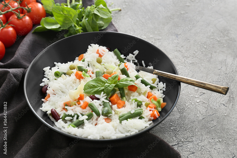 Bowl with tasty rice, beans and vegetables on grunge background