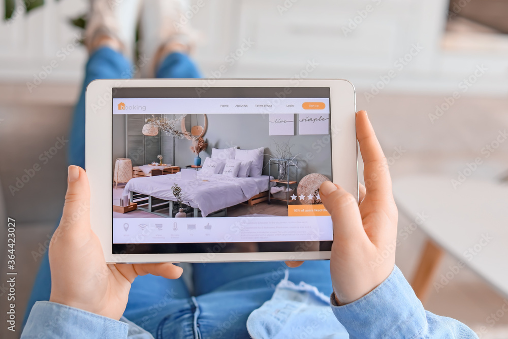 Woman with tablet computer booking room in hotel at home