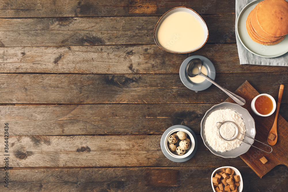 Tasty pancakes with ingredients on wooden background