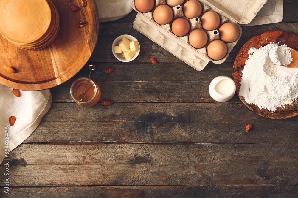 Tasty pancakes with ingredients on wooden background