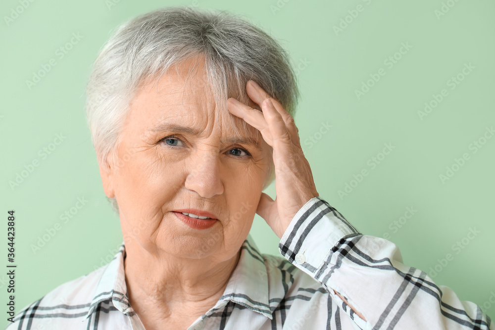 Senior woman suffering from headache on color background
