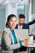 © DragonImages - Portrait of smiling young Asian entrepreneur sitting at office table with cup of coffee after attending meeting with colleagues
