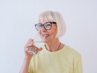 senior woman holding glass of water and drinking water. Healthy lifestyle, sport, anti age concept