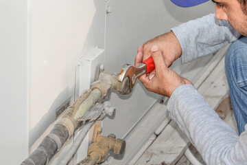 a professional electrician man is fixing the heavy air conditioner by his tools