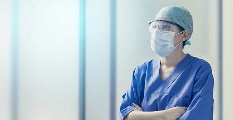 female doctor wearing surgical mask and looking forwards in blurred background with copy space, concept of hospital and health care professionals