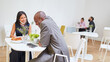 Geschäftsleute sitzen an getrennten Tischen in der Cafeteria