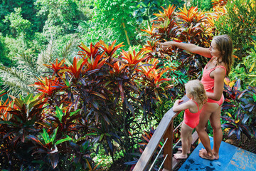 Child, young mother on villa balcony with beautiful tropical view.