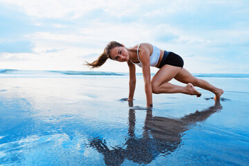 Sporty woman doing mountain climber exercise - run in plank to burn fat. Sunset beach, blue sky background. Healthy lifestyle at tropical island yoga retreat, outdoor activity, family summer vacation.